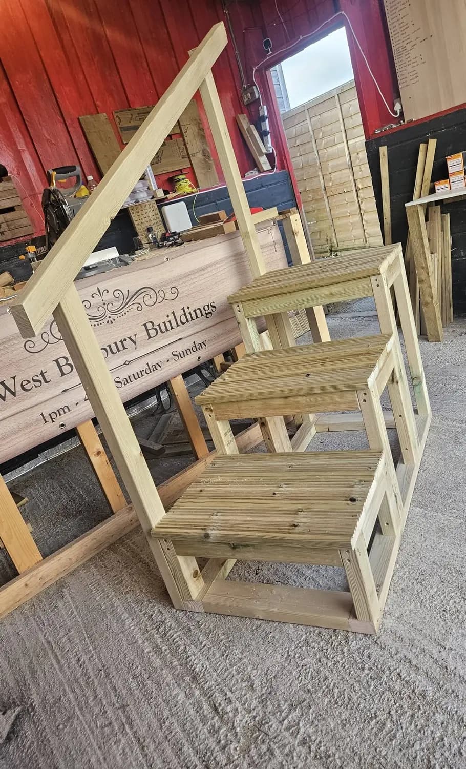 Benches and stools part-built inside the workshop, with the engraved West Banbury Buildings sign behind